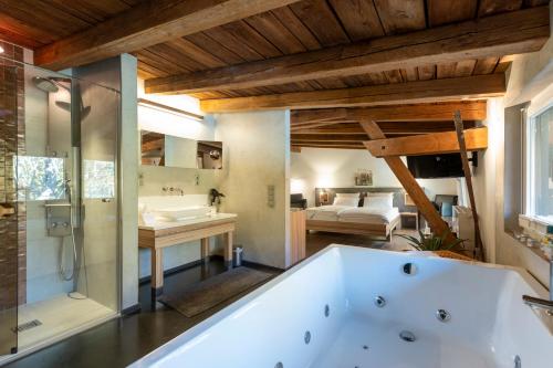 a large bathroom with a tub and a bedroom at Hotel zur Kloster-Mühle in Groß Meckelsen