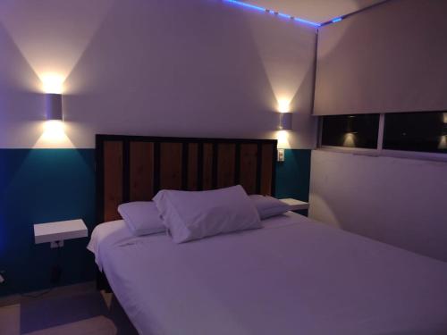 een slaapkamer met een groot wit bed met 2 kussens bij Piso entero, cómodo y moderno in Mexico-Stad