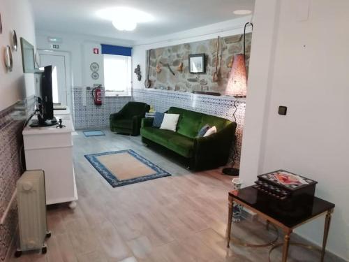 a living room with a green couch and a tv at Casa Aguarela, estilo familiar na Serra da Estrela in São Romão