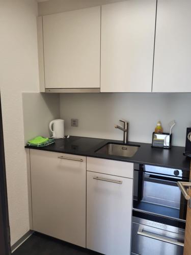 a kitchen with white cabinets and a sink at Jolimont Apartments in Zermatt