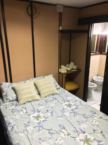 1 dormitorio con 1 cama con colcha de flores en Hostel Parece Mentira en Colonia del Sacramento