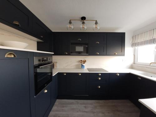 eine schwarze Küche mit schwarzen Schränken und einem Fenster in der Unterkunft Sea View 3 bedroom seaside property in Chichester