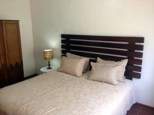 1 dormitorio con 1 cama grande y cabecero de madera en 2 bed guesthouse in Mabelreign - 2012 en Harare