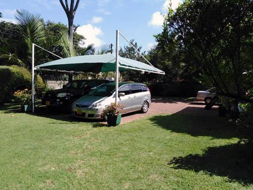 a car parked under a green umbrella in a yard at 2 bed guesthouse in Mabelreign - 2012 in Harare