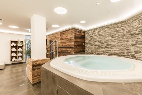 eine große Badewanne in einem Zimmer mit einer Steinmauer in der Unterkunft Grossarler Hof Superior in Großarl