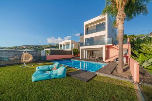 a house with a swimming pool and a palm tree at Villa Candelária by An Island Apart in Ribeira Brava