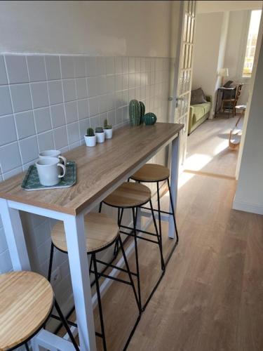 une cuisine avec une table, des tabourets et un comptoir dans l'établissement Studio Nice Le Palais, avec cuisine et espace repas séparés, dans immeuble niçois, Port de Nice, Vieux Nice, Place du pin et Garibaldi, Colline du château, à 2 minutes de la promenade des Anglais, à Nice