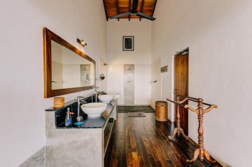 a bathroom with two sinks and a mirror at Aditya Resort in Hikkaduwa