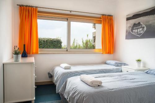 フェレルにあるBest Houses 06 - Gorgeous - Stunning Sea Viewのオレンジ色の窓が備わる客室のベッド2台