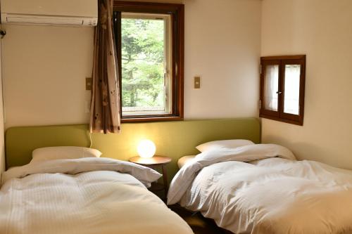 Duas camas num quarto com uma janela em guest house windy em Yamanakako