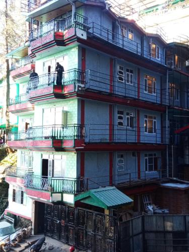 a tall building with balconies and a man sitting on a balcony at Royal king B&B in Shimla