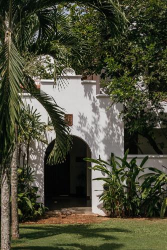 a white building with a door and some trees at Aditya Resort in Hikkaduwa