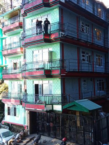 a tall building with two people on the balconies at Royal king B&B in Shimla