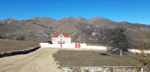 a white house on a hill with mountains in the background at Шахдаг in Qusar