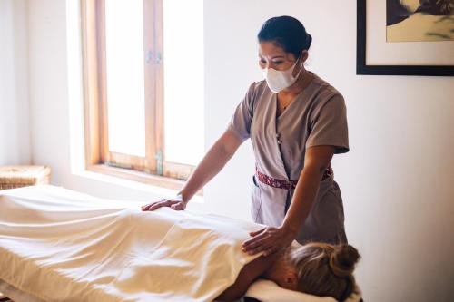a woman in a mask is making a bed at Aditya Resort in Hikkaduwa