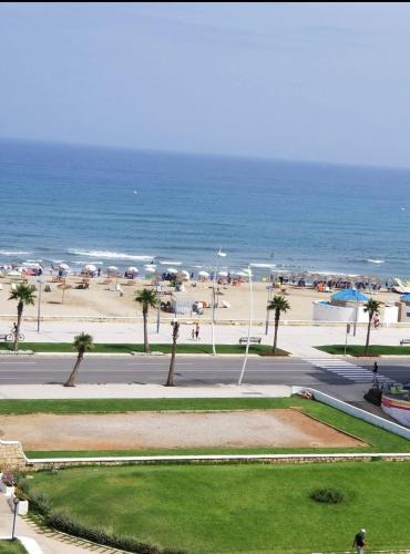a view of a beach with umbrellas and the ocean at Cité Jardin - Appartement Martil avec Climatisation in Martil