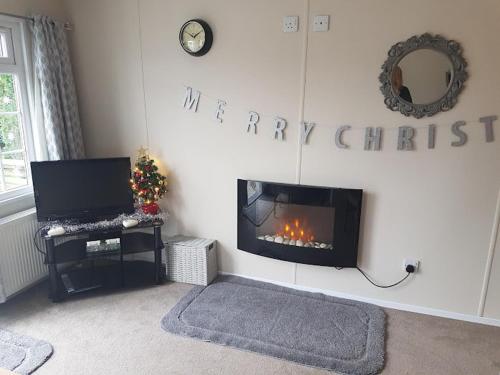 a living room with a fireplace with a happy christmas sign at Lovely 2-Bed Chalet at Robinhood Retreat Free park in Nottingham