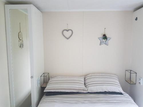 a white bedroom with a bed with a heart on the wall at Lovely 2-Bed Chalet at Robinhood Retreat Free park in Nottingham