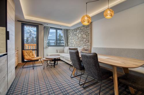 - un salon avec une table, des chaises et un canapé dans l'établissement Chalet Hôtel Turquoise, à La Plagne Tarentaise