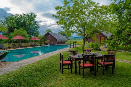 a table and chairs in front of a pool at Gaga Bees Yala in Tissamaharama