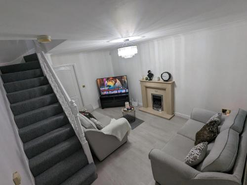 a living room with a staircase and a tv at Greatmindz's home away from home in Bloxwich