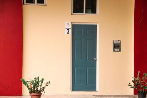 a green door of a house with a red and yellow wall at Hotel Pacific in Tecomán