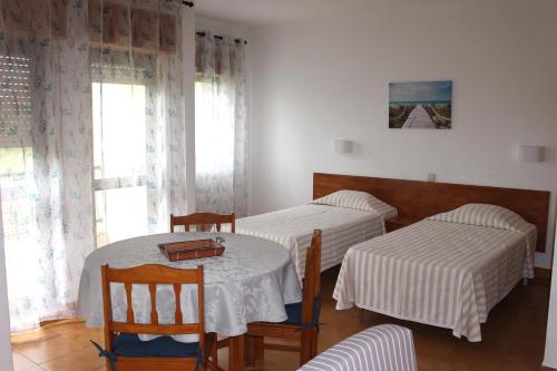 a room with two beds and a table and chairs at Clube Alvorférias in Alvor