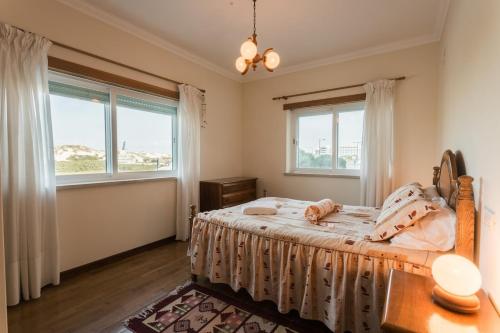 een slaapkamer met een bed en 2 ramen bij Best Houses 09 - Peniche Steps from The Beach in Peniche