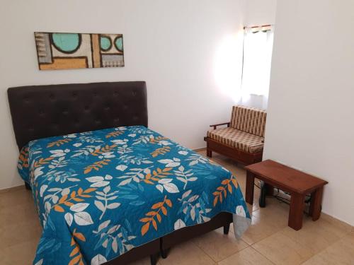 a bedroom with a bed with a blue comforter and a table at Castillo del Lago Carlos Paz - Solo Familiar in Villa Carlos Paz