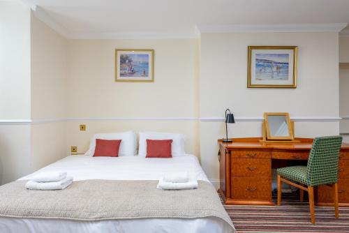 a bedroom with a bed and a desk and a chair at Hotel Prince Regent in Weymouth