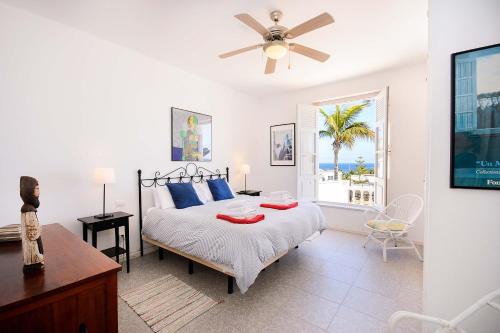 a bedroom with a bed with blue pillows and a ceiling fan at La Casa Del Puerto, Puerto Calero in Puerto Calero
