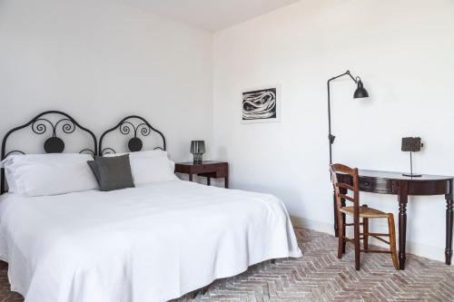 a white bedroom with a white bed and a desk at Hotel Signum in Malfa
