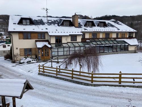 a house with a fence in the snow at Hotel STARÝ MLÝN in Jeseník