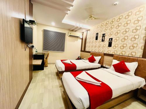 two beds in a hotel room with red pillows at HOTEL SM DECCAN PARK in Shamshabad
