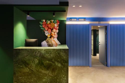 a lobby with blue and green walls and a counter at COEO Pod Hostel - Part of COEO Experience in Málaga