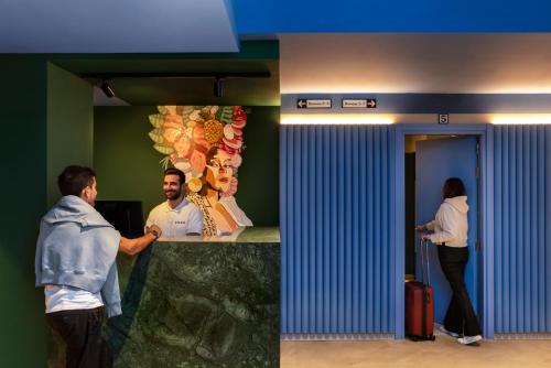 two men and a woman standing at a counter at Coeo Pod Hostel Beatas in Málaga