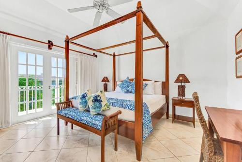 a bedroom with a canopy bed with a chair and a table at Battaleys Mews lovely secure villa 5 minutes from Mullins beach in Saint Peter