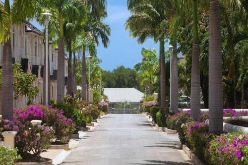 a palm tree lined driveway with flowers and palm trees at Blue Horizon Battaleys Mews Mullins Barbados in Saint Peter
