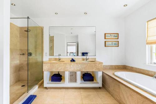 a bathroom with a sink and a tub and a mirror at Battaleys Mews lovely secure villa 5 minutes from Mullins beach in Saint Peter