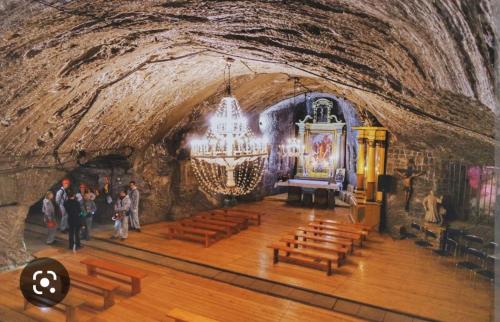 a church in a cave with wooden benches and a chandelier at Apartament Blondynka Miasto Soli Bochnia in Bochnia