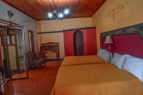 a bedroom with two beds and a chair and a desk at Casa de los Arcángeles in San Cristóbal de Las Casas