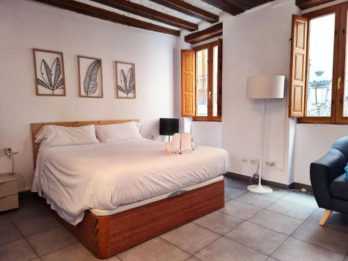 a bedroom with a bed and a chair and windows at Flats Friends Tetuan in Valencia