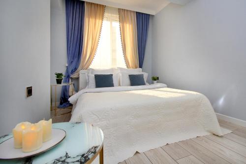 - une chambre avec un grand lit blanc et une fenêtre dans l'établissement Прекрасные апартаменты для путешествующих семей, à Almaty
