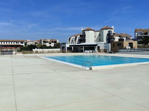 une piscine vide en face de certains bâtiments dans l'établissement Appartement T2 confortable pour 4 pers, RDC, terrasse, parc arboré, piscine, WIFI, parking gratuit - FR-1-195-4, au Barcarès