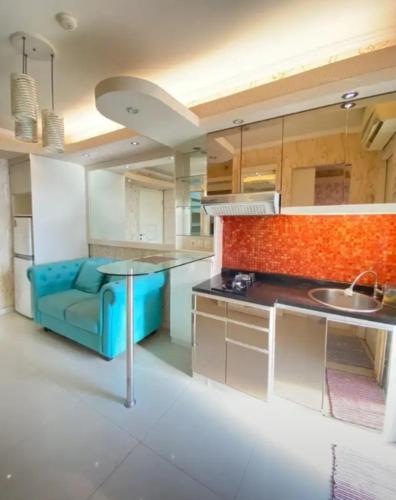 uma cozinha com um sofá azul e um lavatório em Sewa Apartemen Kalibata City by The Best em Jacarta