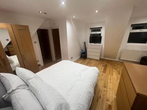 Schlafzimmer mit einem weißen Bett und Holzboden in der Unterkunft Hampden Rd N8,Studio Flat in London