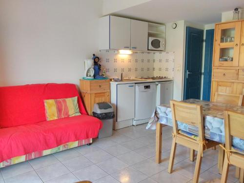 un soggiorno con divano rosso e una cucina di Maison de vacances 5P dans résidence a Le Barcarès