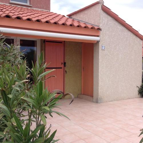 una porta rossa di una casa con patio di Maison de vacances 5P dans résidence a Le Barcarès