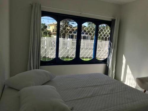 1 dormitorio con cama y ventana en Residencial Casa da Vila apto 3, en Imbituba
