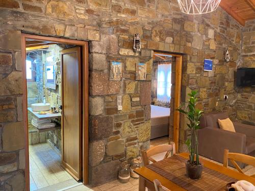 a room with a stone wall with a table and a couch at Caviro on the Beach in Moudhros